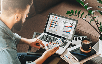 man looking at similar webpages on laptop and mobile phone