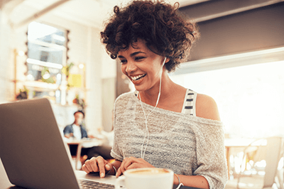 person with earbuds in ears and using a laptop