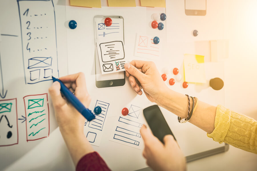 hands marking up whiteboard with design layouts