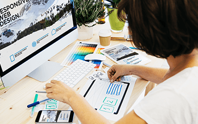 person at desk reviewing hand drawn mock-ups of page layout