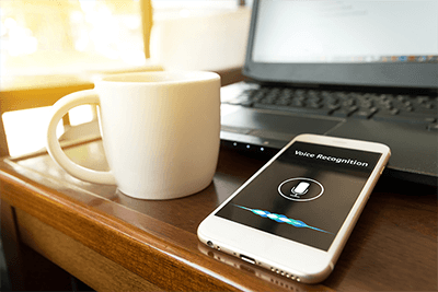 desk with coffee cup and phone showing voice recognition software