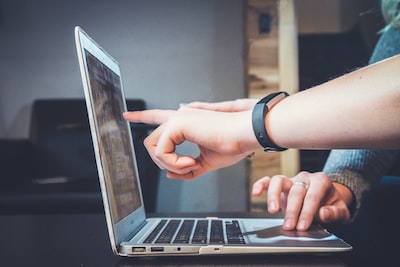 3 hands pointing and typing on a laptop