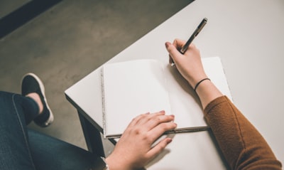 person sitting at desk with notepad and pen