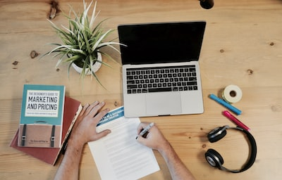 book, laptop and person writing