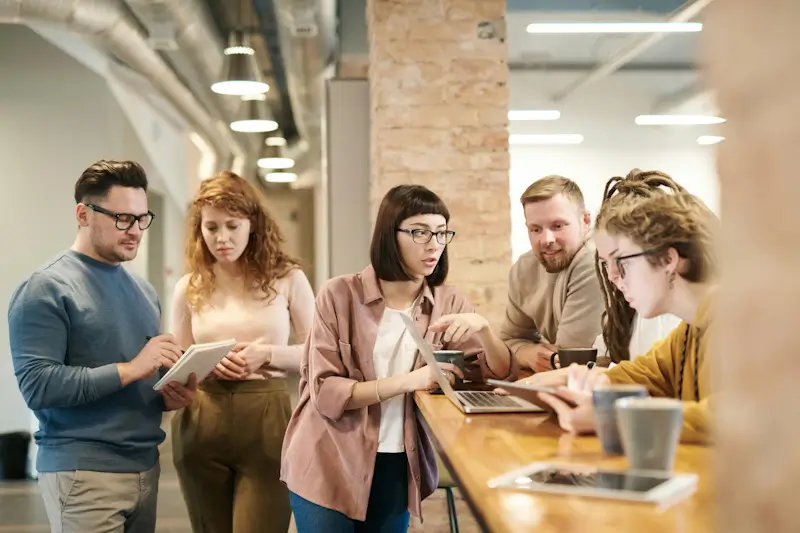 Marketing team collaborating around laptop in modern office setting